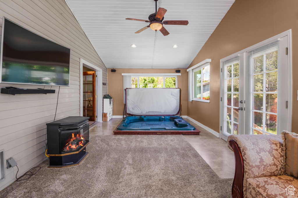 Sunroom featuring a wood stove, a ceiling fan, lofted ceiling, and french doors
