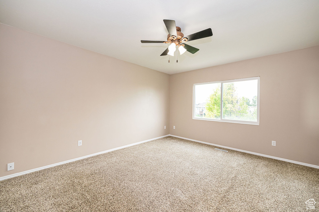 Empty room with carpet flooring, ceiling fan, and baseboards