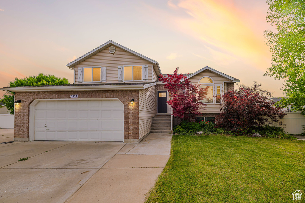 View of front of home with concrete driveway, a front lawn, brick siding, and an attached garage
