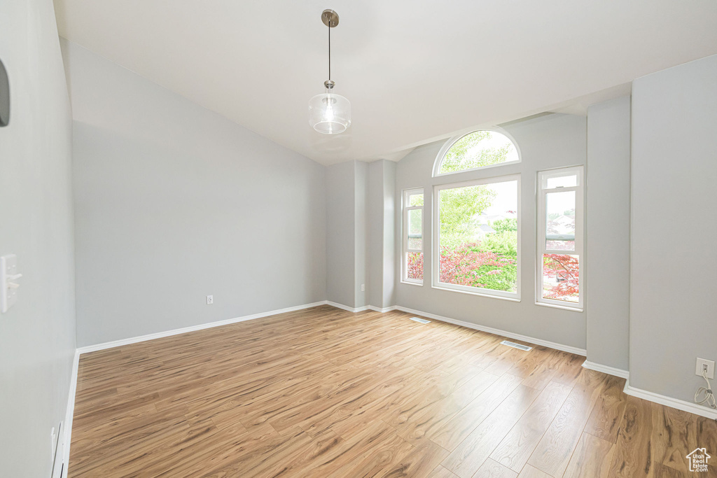 Unfurnished room with light wood-style floors, vaulted ceiling, and baseboards