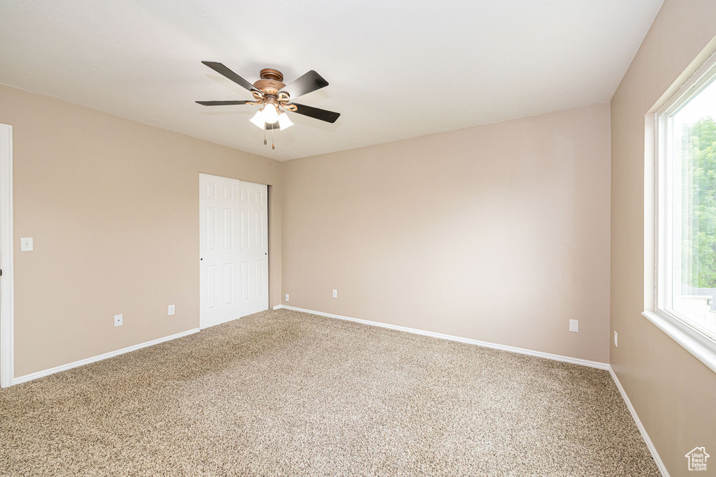 Spare room featuring carpet, healthy amount of natural light, ceiling fan, and baseboards