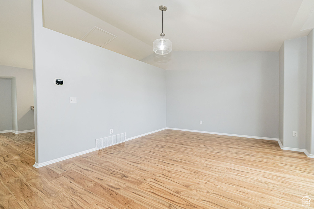 Unfurnished room with light wood-style floors, lofted ceiling, and baseboards