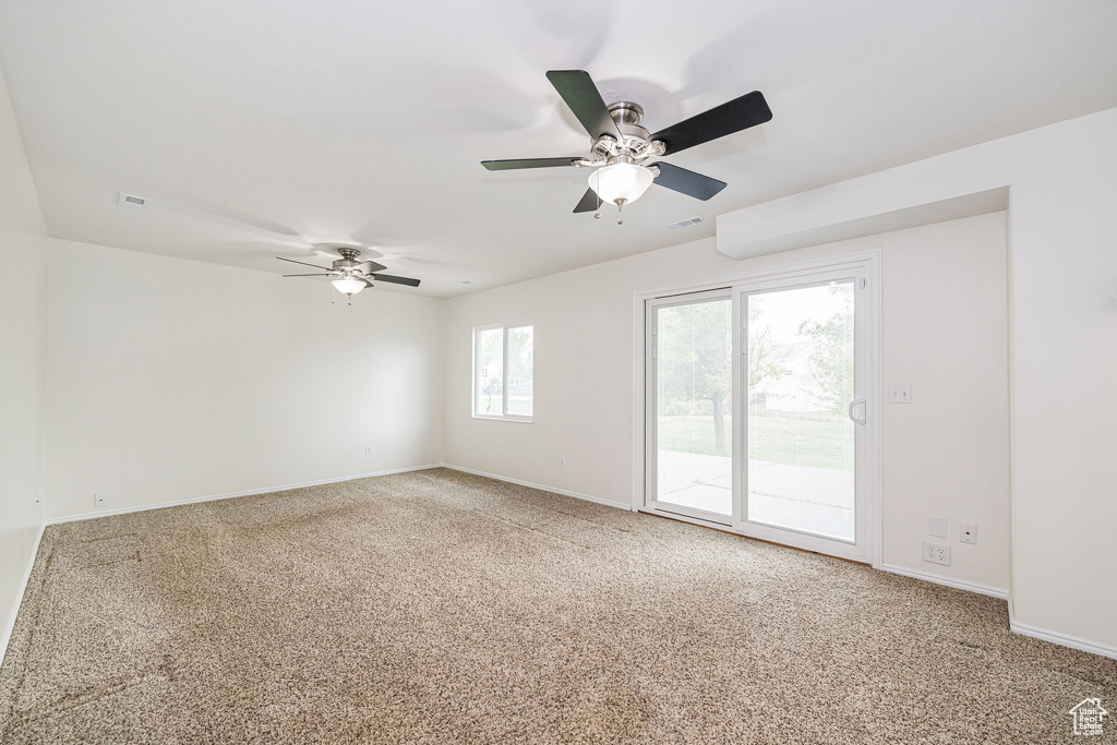 Carpeted empty room featuring ceiling fan and baseboards