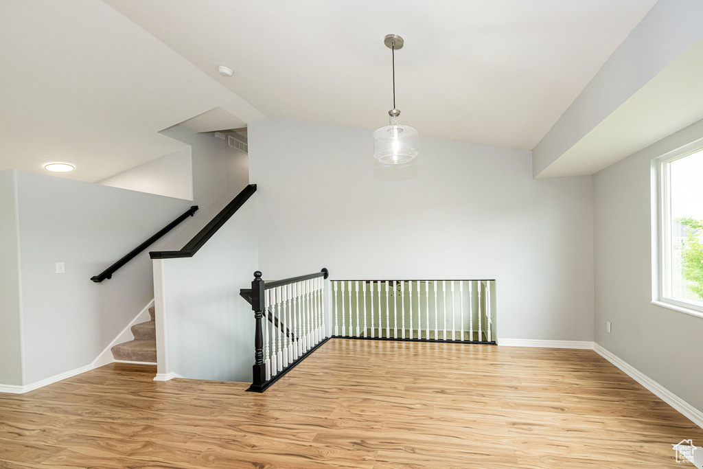 Stairs with wood finished floors, baseboards, and vaulted ceiling