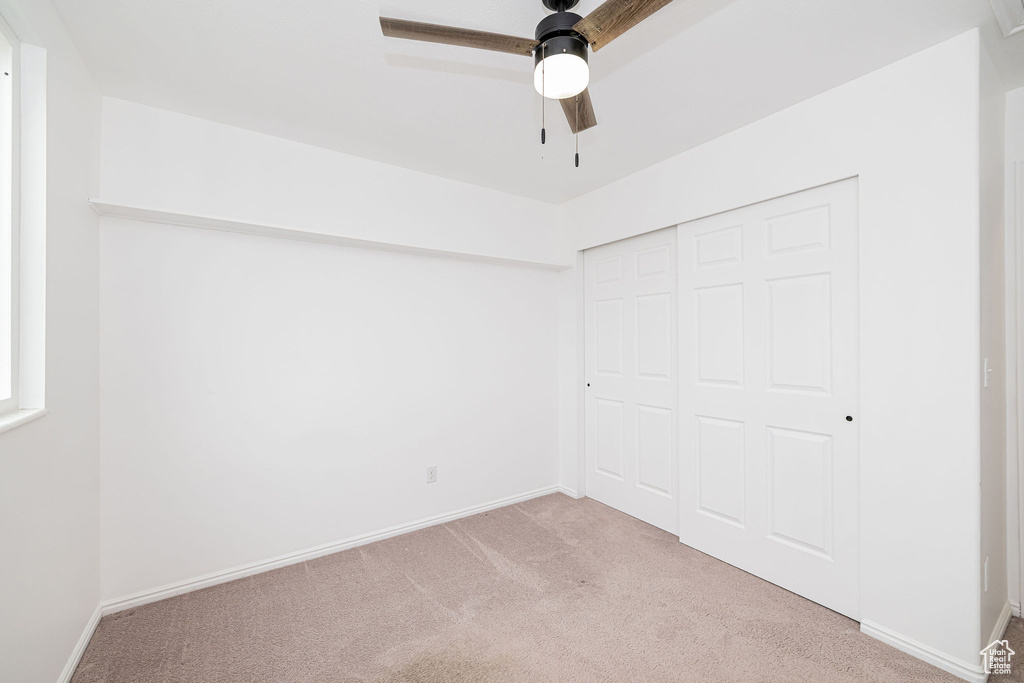Unfurnished bedroom featuring carpet floors, a closet, baseboards, and ceiling fan