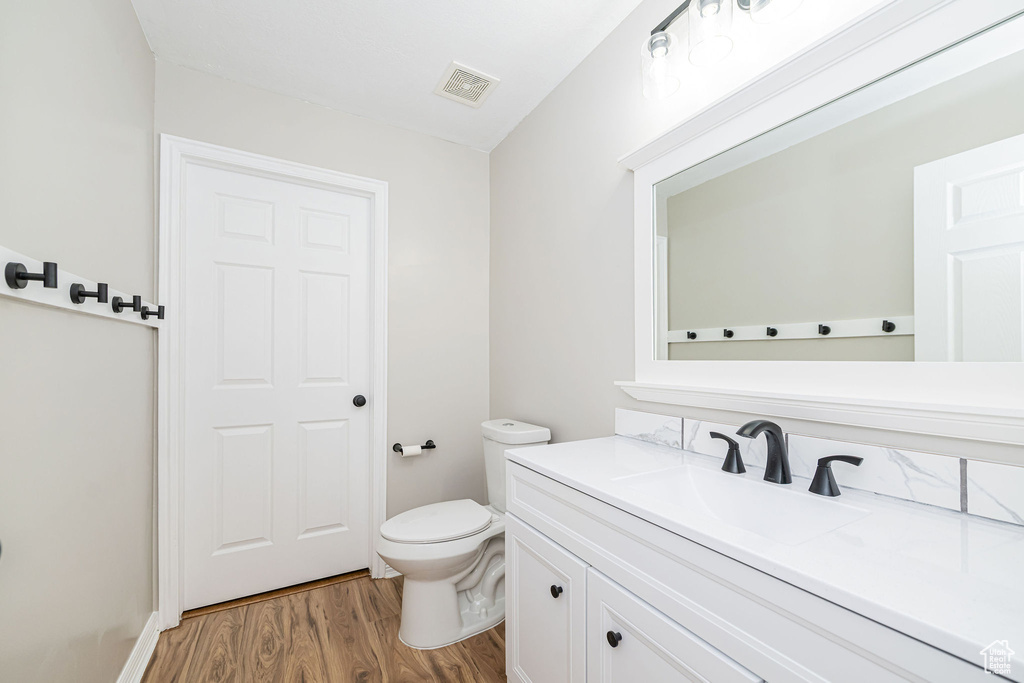 Bathroom with toilet, wood finished floors, and vanity