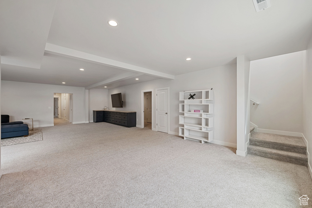Unfurnished living room featuring light colored carpet, recessed lighting, baseboards, stairway, and beam ceiling