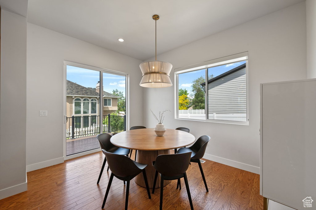 Dining space with baseboards, healthy amount of natural light, wood finished floors, and recessed lighting