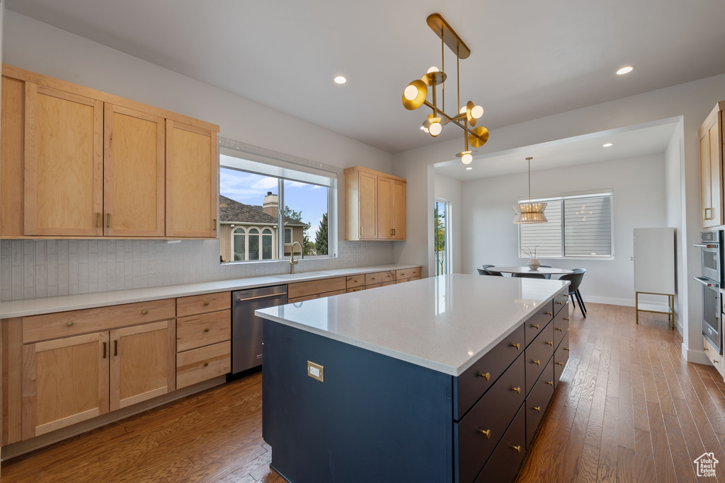 Kitchen featuring appliances with stainless steel finishes, tasteful backsplash, a center island, light brown cabinetry, and a sink