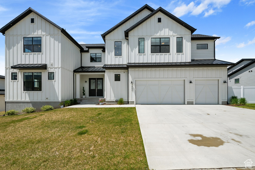 Modern inspired farmhouse with a standing seam roof, board and batten siding, an attached garage, concrete driveway, and metal roof