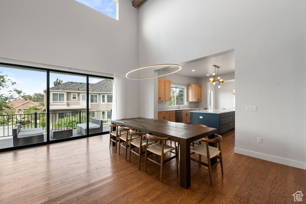 Dining area with a towering ceiling, wood finished floors, a chandelier, and baseboards