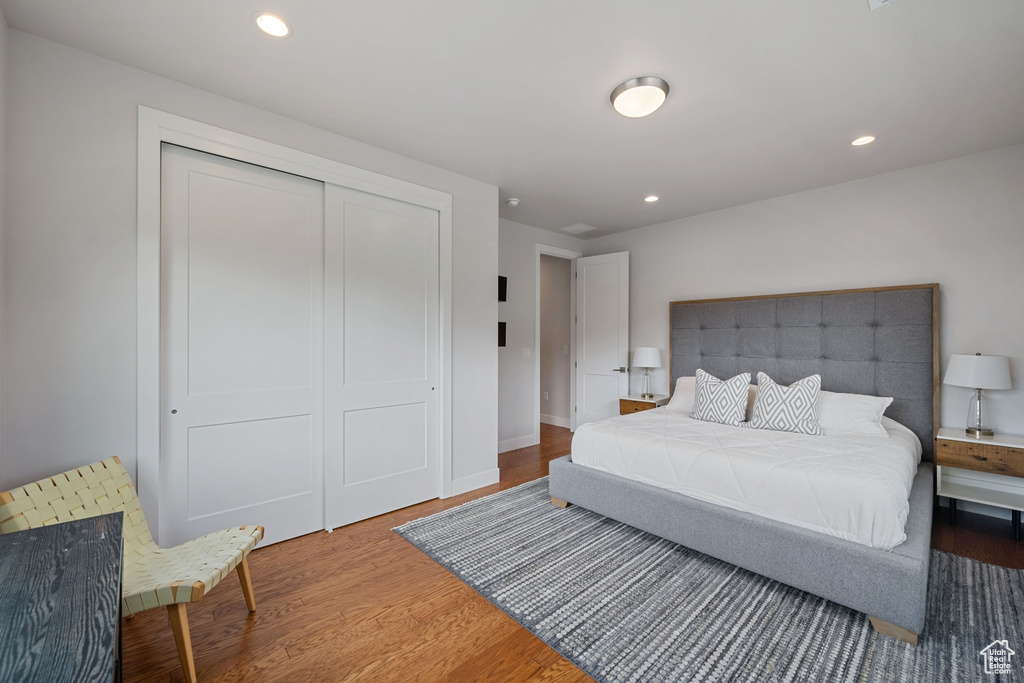 Bedroom with wood finished floors, a closet, recessed lighting, and baseboards