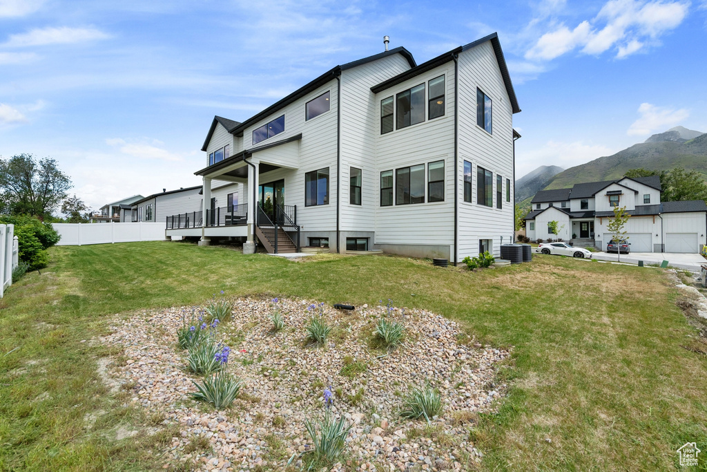 Back of property with central air condition unit, a mountain view, and covered porch