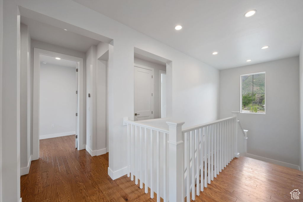 Hall with an upstairs landing, recessed lighting, wood finished floors, and baseboards