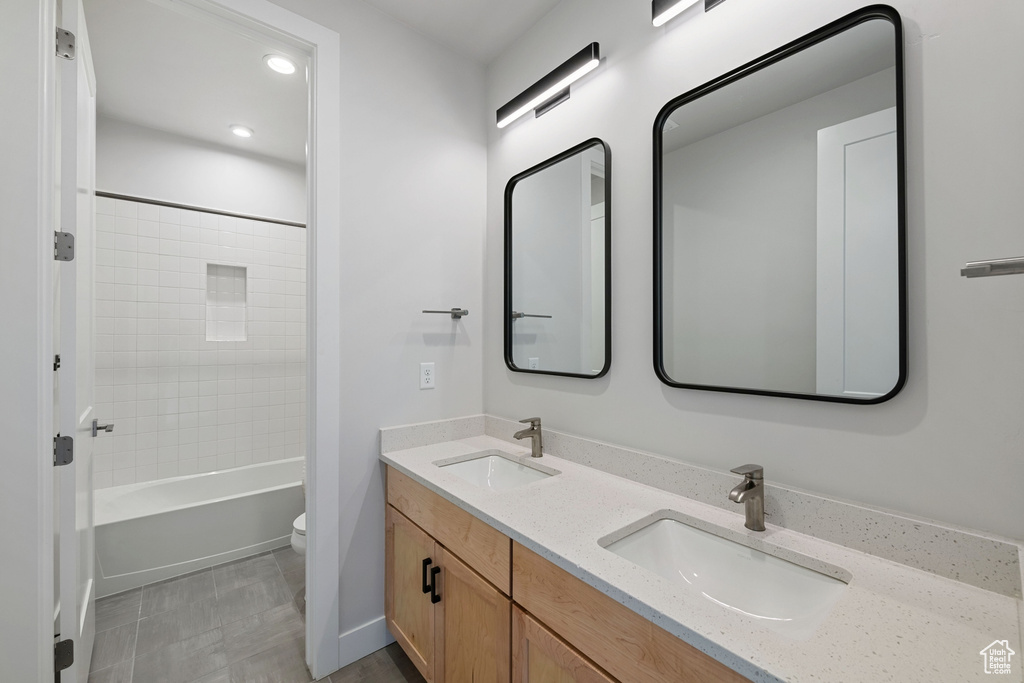 Full bathroom featuring toilet, double vanity, tub / shower combination, and recessed lighting