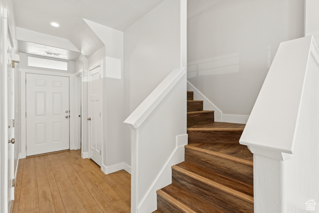 Foyer entrance with stairs, light wood finished floors, and recessed lighting