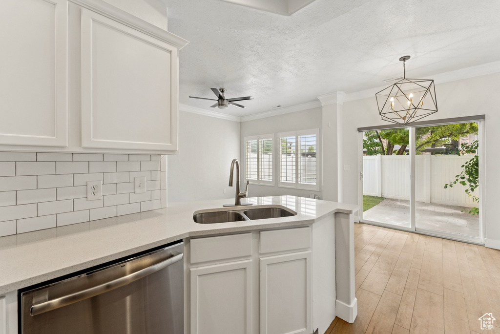 Kitchen with stainless steel dishwasher, a peninsula, ornamental molding, and light countertops