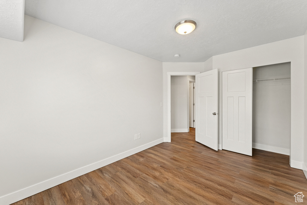 Unfurnished bedroom with wood finished floors and a closet