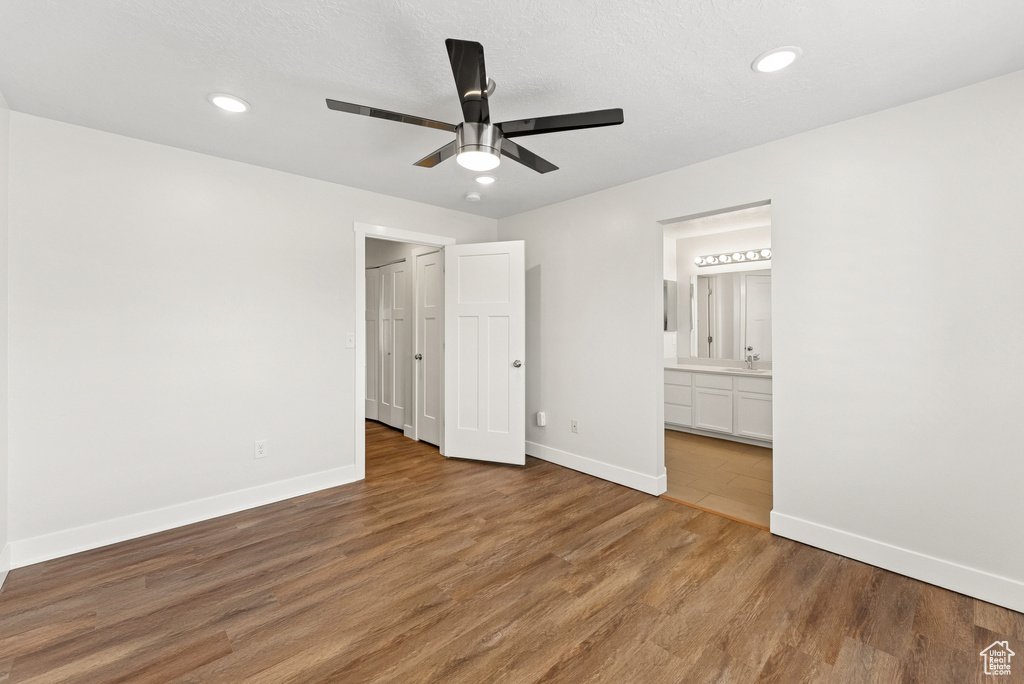 Unfurnished bedroom featuring wood finished floors, recessed lighting, ensuite bath, and a ceiling fan