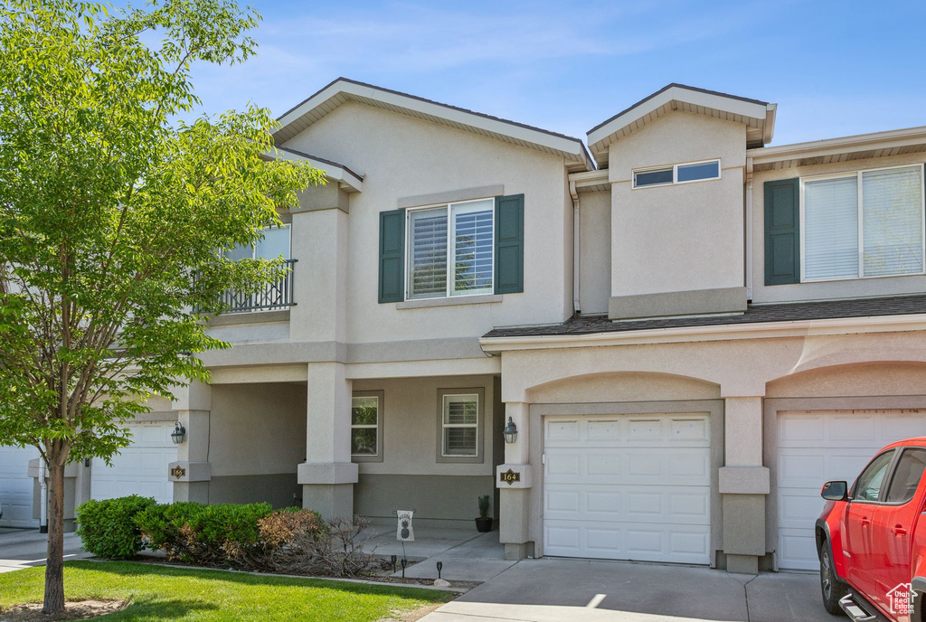 Townhome / multi-family property with stucco siding, an attached garage, and driveway