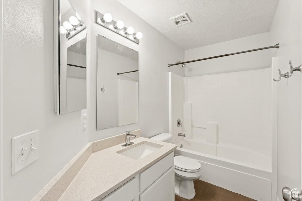 Full bathroom featuring vanity, shower / bathtub combination, a textured ceiling, and wood finished floors