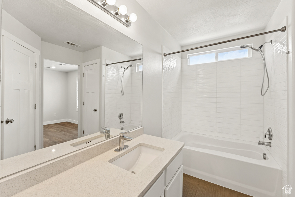Full bath with bathtub / shower combination, vanity, and wood finished floors