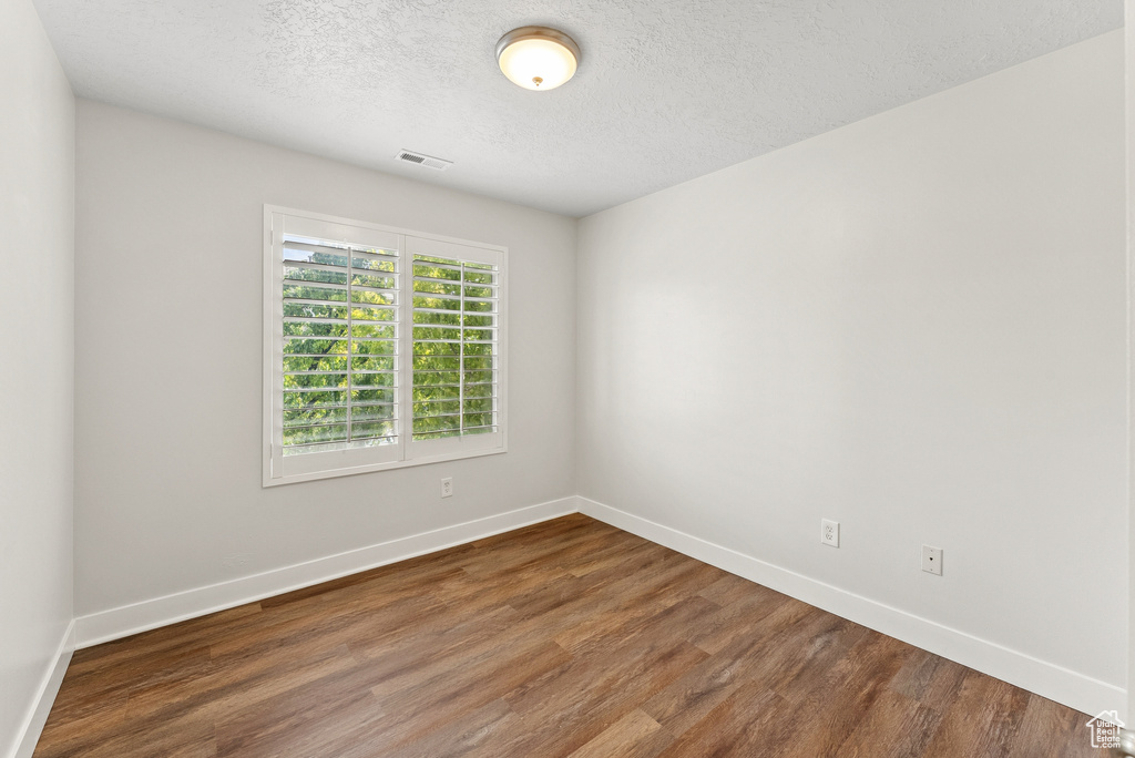 Empty room featuring wood finished floors and a textured ceiling