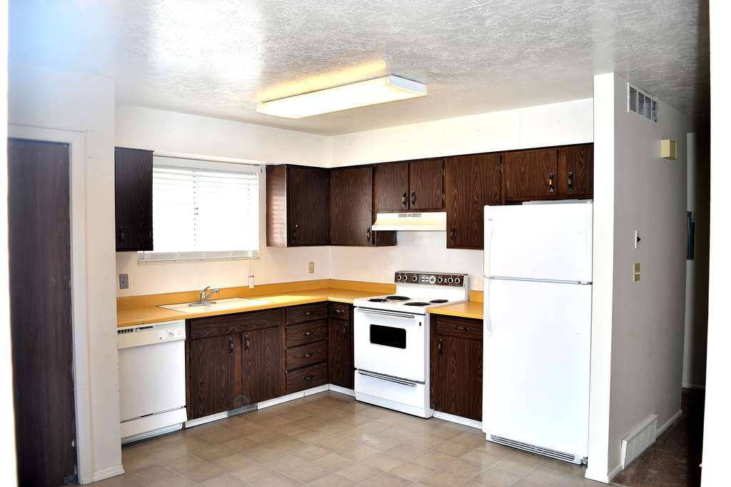Kitchen featuring white appliances, under cabinet range hood, a sink, light countertops, and a textured ceiling