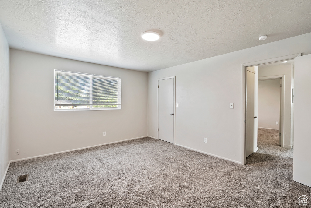 Unfurnished bedroom with carpet, a textured ceiling, and baseboards
