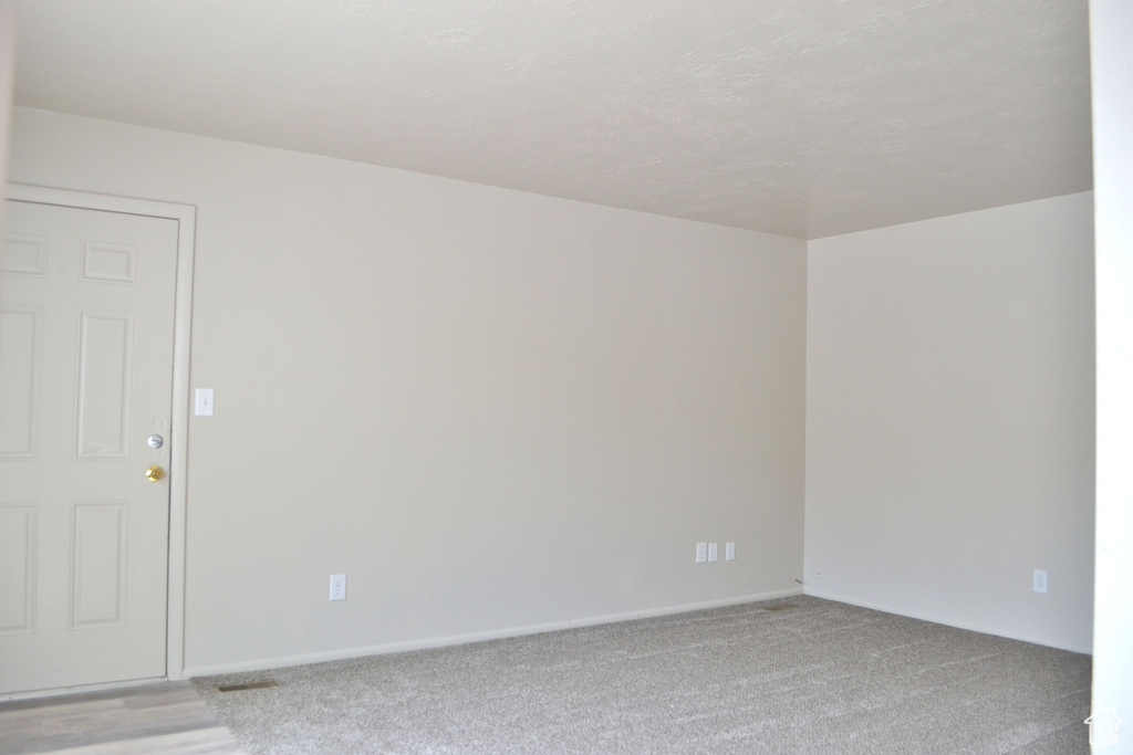 Unfurnished room featuring light carpet and baseboards