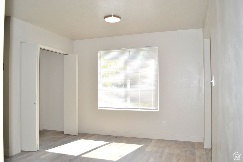 Unfurnished bedroom with light wood-type flooring, a closet, and baseboards