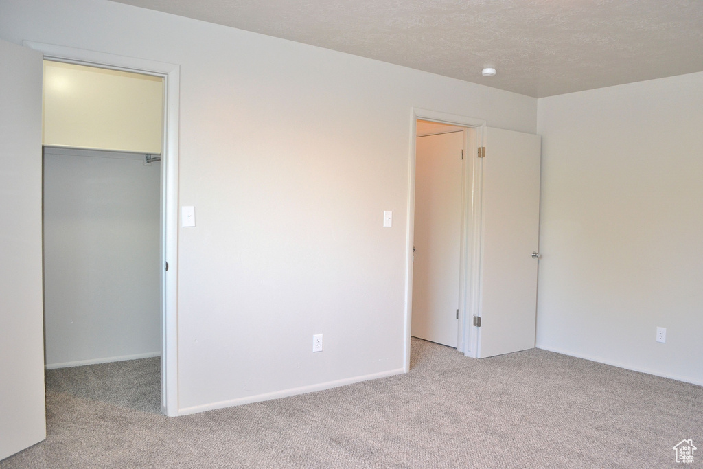 Unfurnished bedroom featuring a walk in closet, carpet floors, and a closet