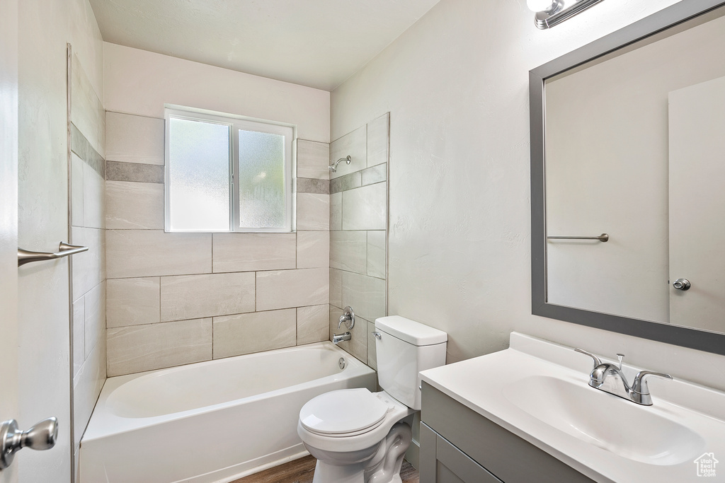 Full bathroom featuring toilet, vanity, washtub / shower combination, and wood finished floors