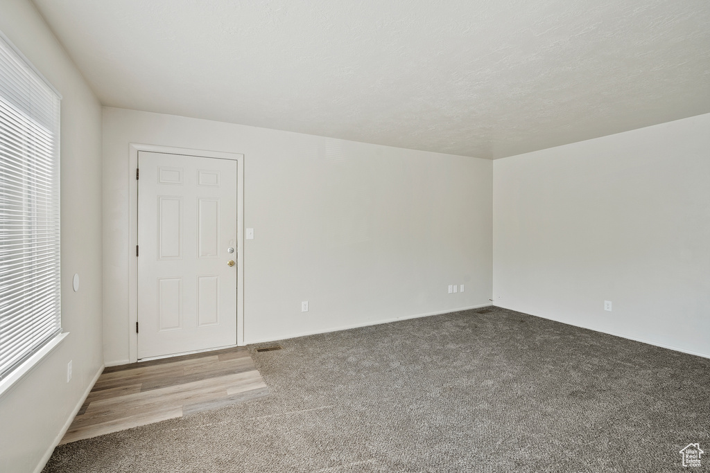 Spare room featuring carpet flooring, plenty of natural light, and baseboards