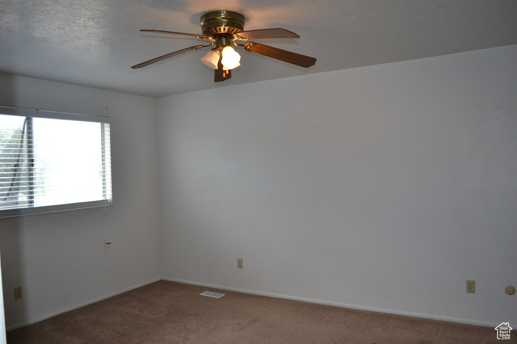 Empty room with carpet, a ceiling fan, and baseboards