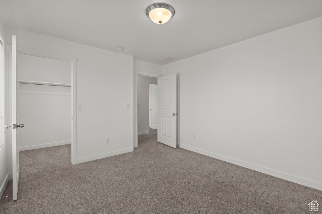 Unfurnished bedroom featuring carpet floors, baseboards, a closet, and a walk in closet