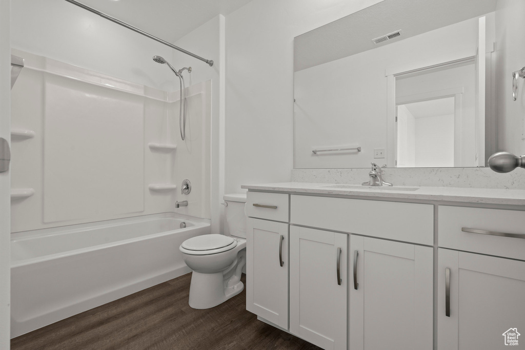 Bathroom featuring wood finished floors, vanity, toilet, and shower / washtub combination