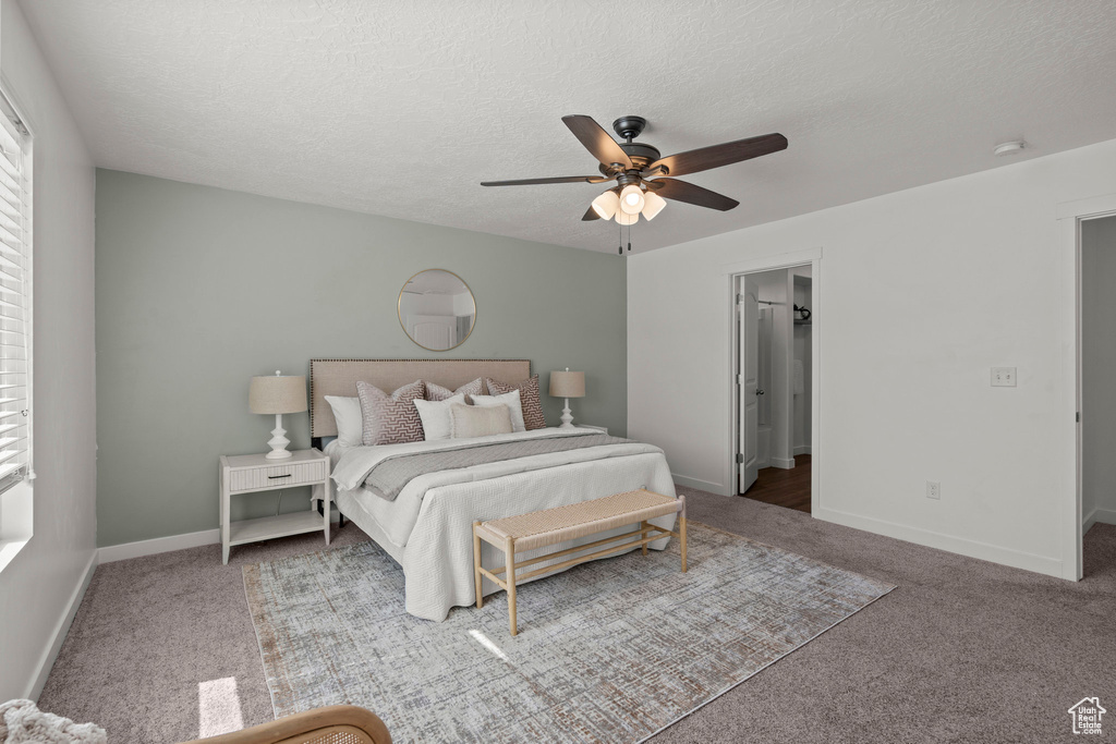 Bedroom featuring carpet floors, baseboards, a textured ceiling, and a ceiling fan