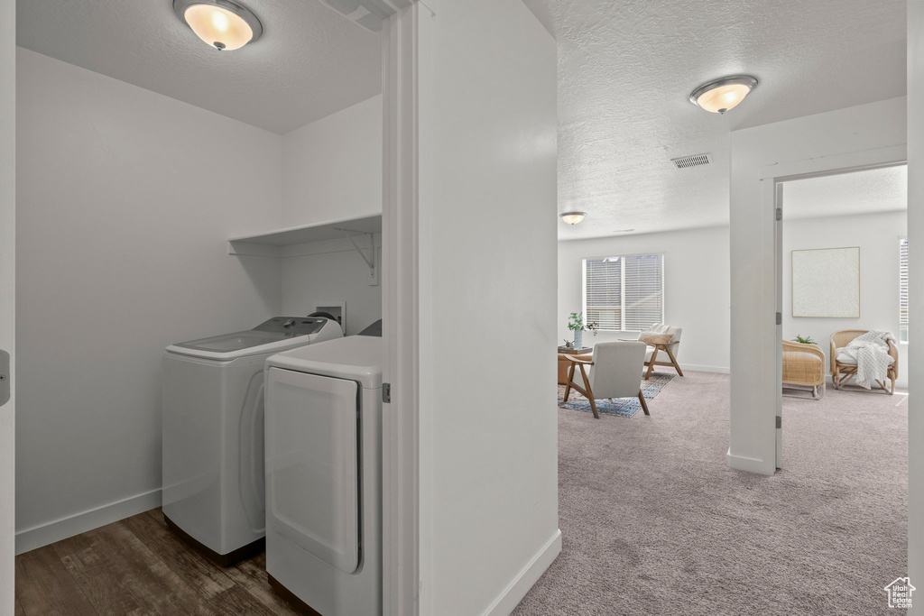 Laundry room with washer and clothes dryer, a textured ceiling, baseboards, and dark colored carpet