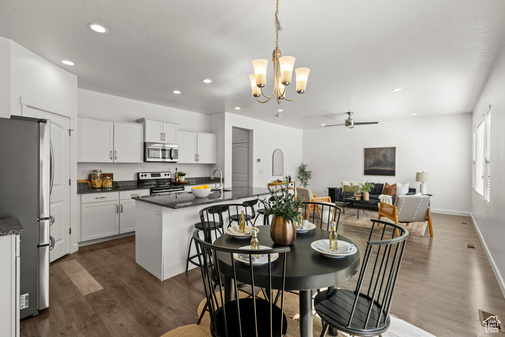 Dining room featuring dark wood-type flooring, recessed lighting, a chandelier, a ceiling fan, and baseboards