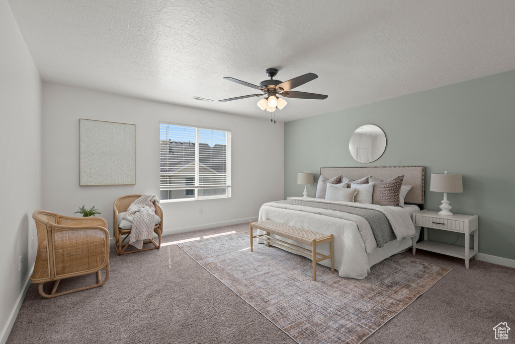 Bedroom with carpet flooring, baseboards, a textured ceiling, and a ceiling fan
