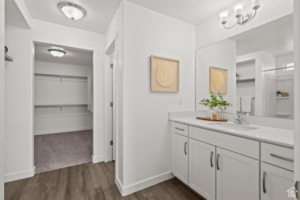 Bathroom with vanity, a walk in closet, wood finished floors, and baseboards