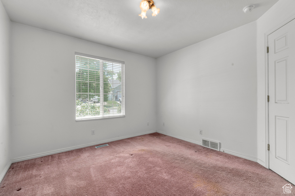 Spare room with carpet flooring, baseboards, and a chandelier