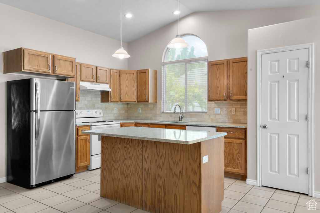 Kitchen featuring freestanding refrigerator, electric range, under cabinet range hood, a sink, and light tile patterned floors