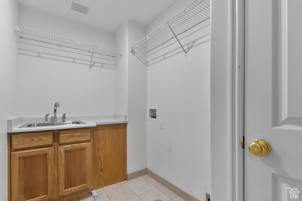 Laundry room featuring hookup for a washing machine, light tile patterned floors, cabinet space, and baseboards