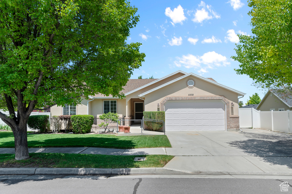 View of front facade with an attached garage, driveway, and stucco siding