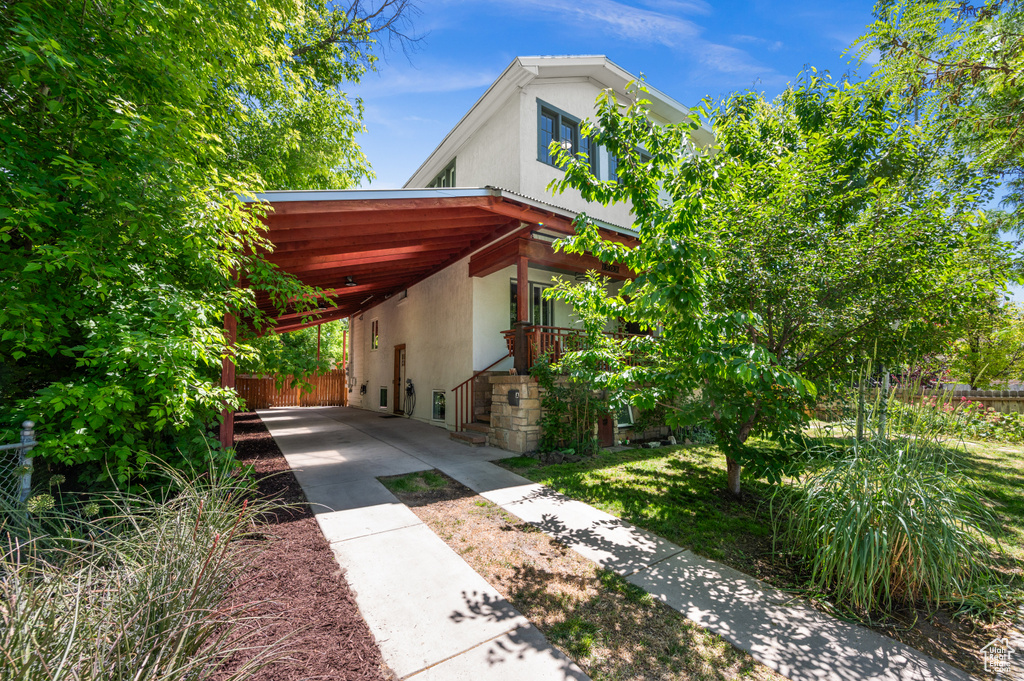 View of property exterior featuring stucco siding, an attached carport, and driveway