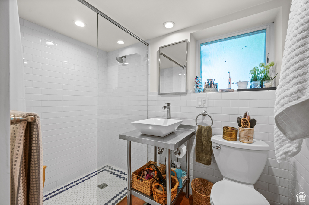 Bathroom featuring a sink, tile walls, walk in shower, toilet, and recessed lighting