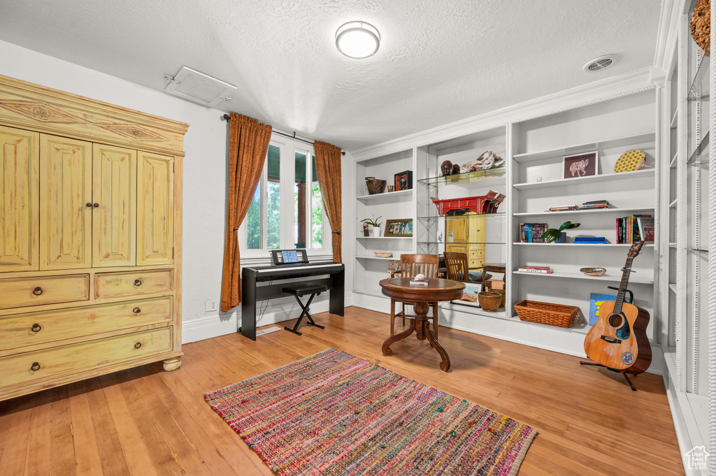 Living area featuring a textured ceiling, light wood-style floors, and baseboards