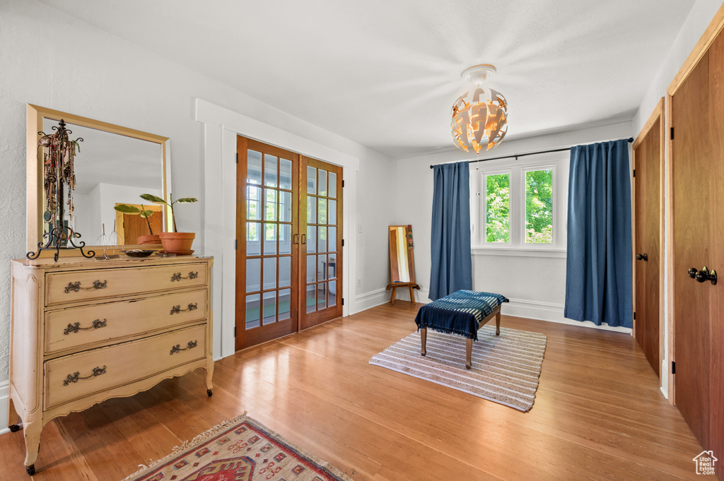 Sitting room with french doors, light wood finished floors, a chandelier, and baseboards